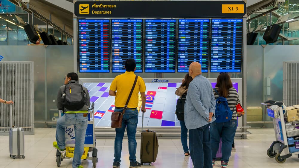 Travelers checking an airport departures board before their flight