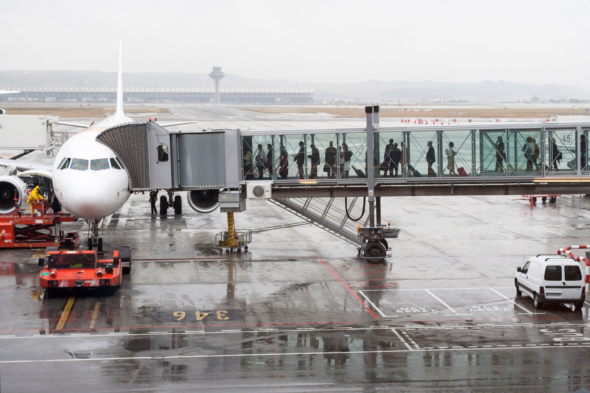 Passengers boarding a flight through a jet bridge at an airport gate